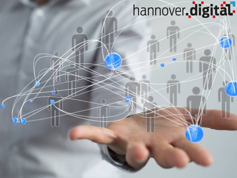 Darstellung eines Netzwerks bestehend aus farbigen Punkten und Menschenkonturen, das über einer Handfläche schwebt.